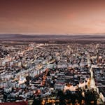 Stunning aerial view of Deva, Romania, captured at dusk with city lights illuminating the urban landscape.